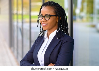 Portrait of an African American business woman with rastafarian dreadlocks and eyeglasses looking away with confidence while thinking outdoors