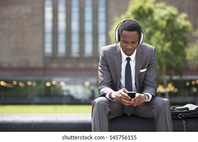 Portrait of African American Businessman listening to music with headphones outdoors