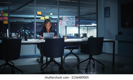 Portrait of African American Businesswoman Working on Laptop Computer in Big City Office Late in the Evening. Female Executive Director Managing Digital e-Commerce Project, Finance Analysis - Powered by Shutterstock