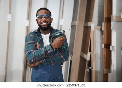 Portrait African American carpenter holding electric screwdriver with wood timber at wood factory	