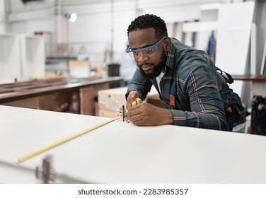 Portrait African American carpenter holding tape measure at wood factory - Powered by Shutterstock