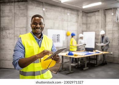 Portrait of African American civil engineer or construction worker holding tablet computer. - Shutterstock ID 2302971327