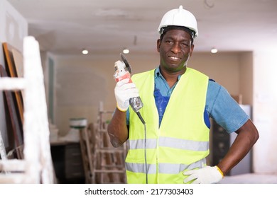Portrait Of An African American Contractor Standing On A Construction Site Indoors With An Electric Angle Grinder In His Hands
