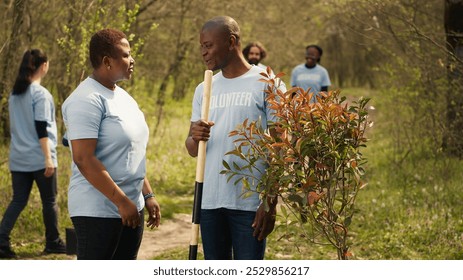 Portrait of african american couple fighting to preserve natural environment by planting trees, collecting rubbish and cultivating consciousness. Volunteers save the planet. Camera A. - Powered by Shutterstock