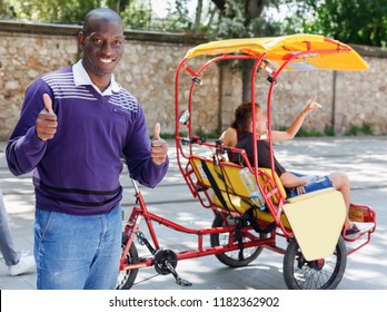 Portrait of African American driver of pedicab offering touristic tour of city