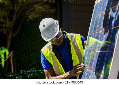 Portrait Of African American Electrician Engineer In Safety Helmet And Uniform Are Checking Solar Panels Condition.