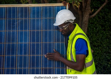 Portrait Of African American Electrician Engineer In Safety Helmet And Uniform Are Checking Solar Panels Condition.