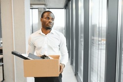 Portrait Of African American Employee Being Fired Closing Laptop With Business Data While Holding Tray With Personal Belongings Before Leaving. Laid Off Startup Worker Cleaning Desk Before Going Home.