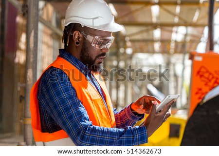 Portrait of African american engineer checking documents on tablet computer