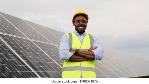 Portrait Of African American Engineer On Background Field Of Photovoltaic Solar Panels. Black Man Technician At Solar Station.