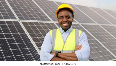 Portrait Of African American Engineer On Background Field Of Photovoltaic Solar Panels. Black Man Technician At Solar Station.