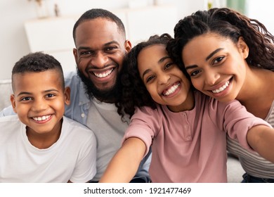 Portrait of african american family taking a selfie together at home indoors. Happy parents posing with their children and smiling at camera, point of view. Bonding And Lifestyle Concept.