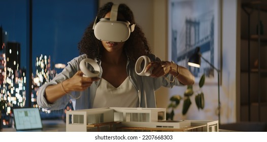 Portrait Of African American Female Architect Or Student Using A Virtual Reality VR Headset To Work On A House Project Late At Night, Preparing For Presentation With A Client