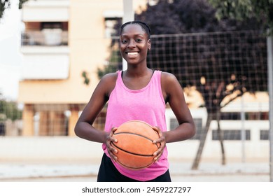 Portrait of an African American female basketball player. She laughs holding the basketball - Powered by Shutterstock