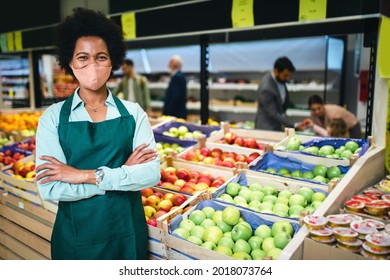 Portrait Of African American Female Employee In Grocery Store. She Is Wearing Protective Face Mask Due To Covid-19 Pandemic.