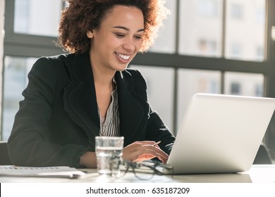 Portrait Of African American Female Expert Analyzing Printed Business Report While Sitting At Desk In The Office