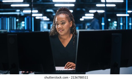 Portrait Of African American Female IT Specialist Working On Desktop In Data Center. System Administrator Works On Web Services, Cloud Computing, Server Analytics, Cyber Security Maintenance, SAAS