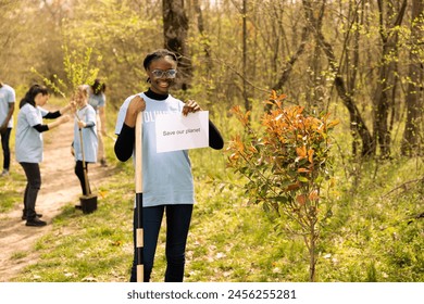 Portrait of african american girl holding banner with save our planet message, spreading ecological justice and awareness. Teenager activist posing with a poster to fight environmental pollution. - Powered by Shutterstock