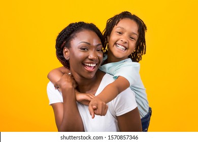 Portrait Of African American Girl With Mother Pointing Finger To The Camera At You, Laughing Over Yellow Background