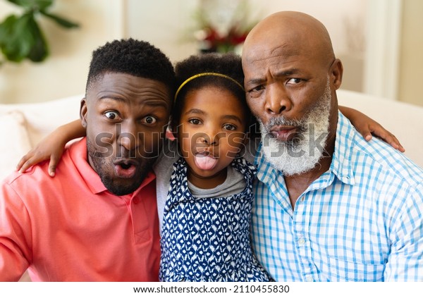 Portrait of african american grandfather,\
father and granddaughter making silly faces at home. family, love\
and togetherness concept,\
unaltered.