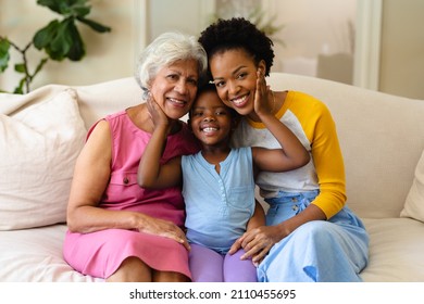Portrait of african american grandmother, mother and granddaughter smiling sitting on couch at home. family, love and togetherness concept, unaltered.