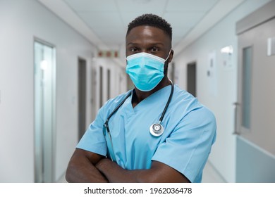 Portrait of african american male doctor wearing face mask standing in hospital corridor. medicine, health and healthcare services during coronavirus covid 19 pandemic. - Powered by Shutterstock