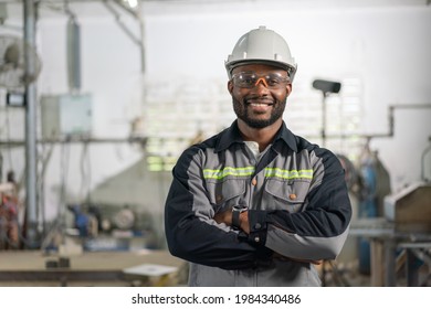 Portrait of African American male engineer in uniform smiling and standing cross arm in industrial factory