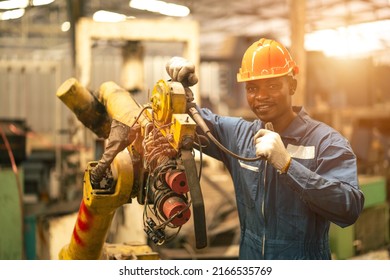 Portrait of African American male engineer in uniform smiling with the machine at industrial factory - Powered by Shutterstock