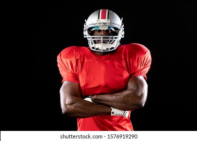 Portrait of an African American male American football player wearing a team uniform, pads and a helmet standing with arms crossed - Shutterstock ID 1576919290