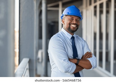Portrait of african american man architect at building site looking at camera. Confident construction manager wearing hardhat. Successful mature civil engineer at construction site with copy space.