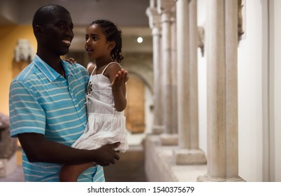 Portrait Of African American Man And His Daughter At Hall Of Art Museum Among Exhibits Of Antiquity