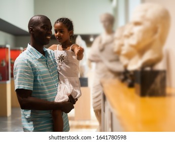 Portrait Of African American Man And His Daughter At Hall Of Art Museum Among Exhibits Of Antiquity