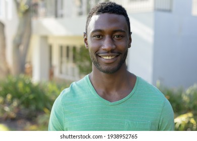 Retrato de un hombre afroamericano mirando la cámara y sonriendo en la soleada terraza del jardín. permanecer en casa aislado durante el bloqueo de cuarentena.