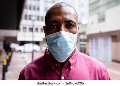 Portrait Of African American Man Out And About In The City Streets During The Day, Wearing A Face Mask Against Air Pollution And Covid19 Coronavirus, Looking Straight Into A Camera.