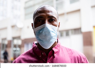 Portrait of African American man out and about in the city streets during the day, wearing a face mask against air pollution and covid19 coronavirus, looking straight into a camera. - Powered by Shutterstock