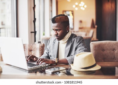Portrait of african american man sitting at a cafe and working on a laptop. - Shutterstock ID 1081811945