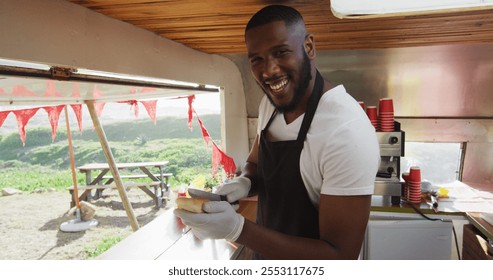 Portrait of african american man smiling while preparing hot dogs in the food truck. food truck and street food concept - Powered by Shutterstock