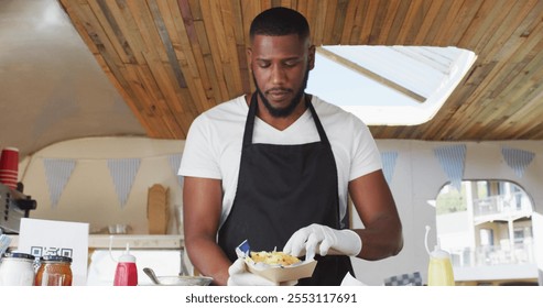 Portrait of african american man wearing apron smiling while serving food in food truck. food truck and street food concept - Powered by Shutterstock