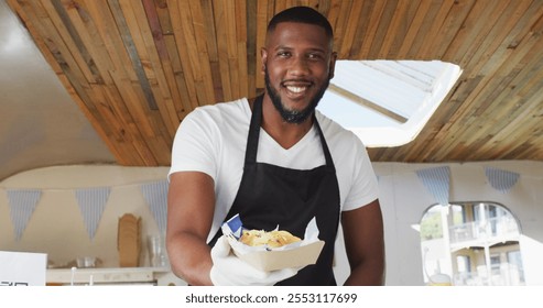 Portrait of african american man wearing apron smiling while serving food in food truck. food truck and street food concept - Powered by Shutterstock