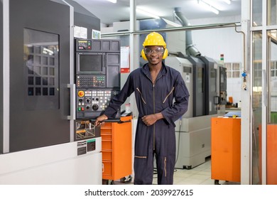 Portrait of African American mechanic engineer worker wearing safety equipment beside the automatic lathe machine in the manufacturing factory