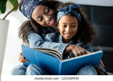 Portrait Of African American Mother And Daughter Looking At Family Photo Album At Home