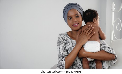 Portrait Of African American Mother Holding Her Baby Girl, Black Female Cancer Patient In Healing With Chemotherapy Holding Her Baby On Hands