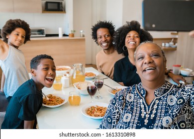 Portrait of african american multigenerational family taking a selfie together with mobile phone while having dinner at home. Family and lifestyle concept. - Powered by Shutterstock