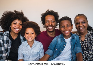 Portrait of african american multigenerational family looking at camera while sitting on sofa couch at home. Family and lifestyle concept. - Powered by Shutterstock