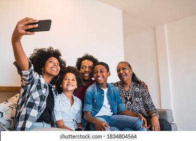 Portrait of african american multigenerational family taking a selfie together with mobile phone at home. Family and lifestyle concept. - Powered by Shutterstock