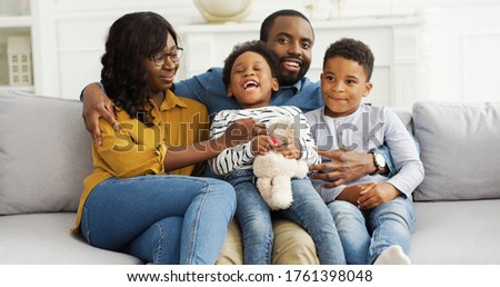 Portrait of African American parents with little kids resting on sofa at home. Family Celebrating 4th Of July, Patriotic holiday Day.
