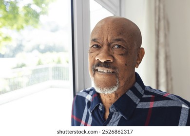 Portrait of african american senior man looking out window at home. Lifestyle, retirement, senior lifestyle and domestic life, unaltered. - Powered by Shutterstock