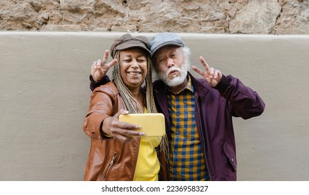 Portrait of African american senior woman and asian mature taking a selfie with smartphone. Happy multiracial couple - Powered by Shutterstock