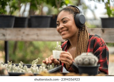 Portrait african american small business gardener woman looking at young plant gardening with potted plants taking care small tree, startup, flower care in greenhouse at garden shop - Shutterstock ID 2394356923