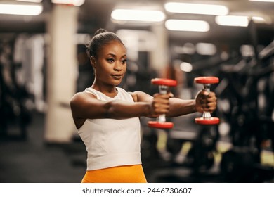 Portrait of an african american sportswoman exercising shoulders with dumbbells at gym. - Powered by Shutterstock